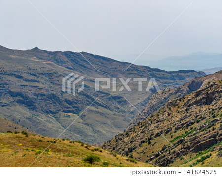 Wide valley surrounded by steep, rocky mountains Wide valley surrounded by steep, rocky mountains 141824525