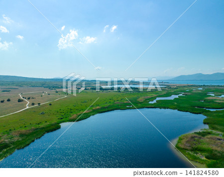 Wide lake in grassy wetland area with distant hills Wide lake in grassy wetland area with distant hills 141824580