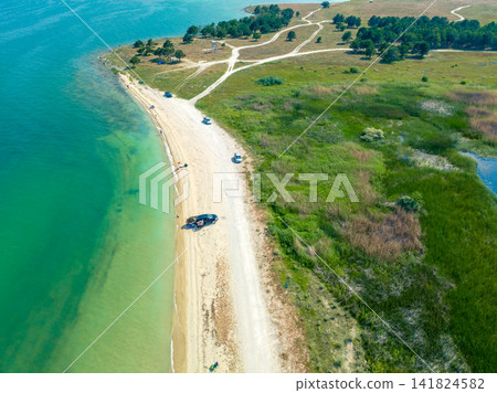 Drone shot shows coastal drive beside clear sea and grassy land Drone shot shows coastal drive beside clear sea and grassy land 141824582
