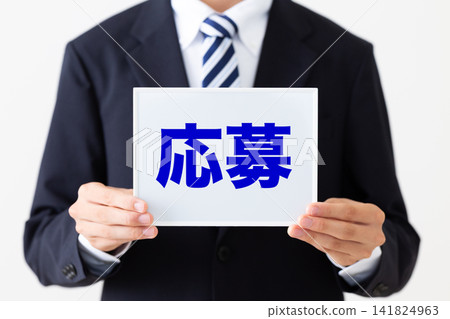 身穿西裝的年輕商人,手持一塊寫滿求職申請的白板。 身穿西裝的年輕商人,手持一塊寫滿求職申請的白板。 141824963