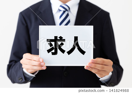 一位身穿西裝的年輕商人,手持白板,上面刊登著徵才廣告。 一位身穿西裝的年輕商人,手持白板,上面刊登著徵才廣告。 141824988