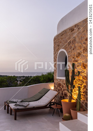 Villa sun loungers in Ibiza, two loungers below an arched window on the exterior. Villa sun loungers in Ibiza, two loungers below an arched window on the exterior. 141825081