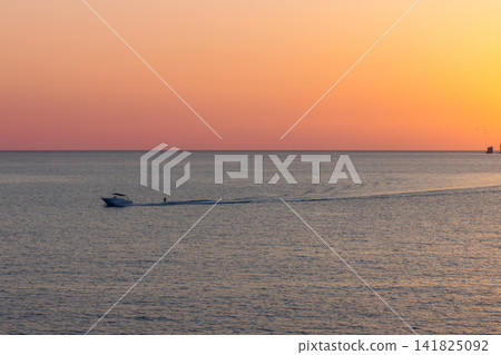 Motor yacht in Ibiza, Spain, small yacht moving left with a long curved wake. Motor yacht in Ibiza, Spain, small yacht moving left with a long curved wake. 141825092