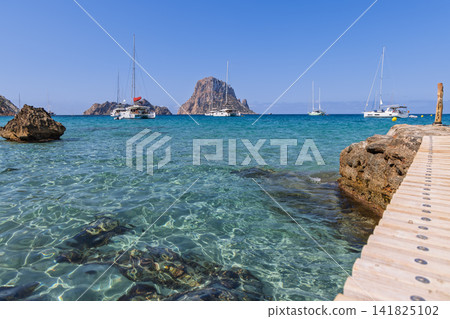 Es Vedra and Es Vedranell opposite Cala d Hort with submerged rocks and wooden dock. Es Vedra and Es Vedranell opposite Cala d Hort with submerged rocks and wooden dock. 141825102