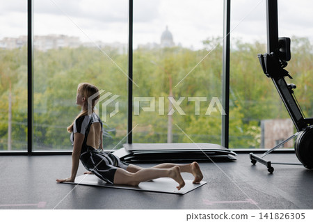 Woman doing cobra pose on yoga mat in gym Woman doing cobra pose on yoga mat in gym 141826305