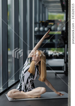 Woman stretching in yoga pose on mat in gym Woman stretching in yoga pose on mat in gym 141826315