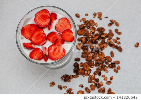 Smoothie with strawberries and granola on a light surface during the daytime in a kitchen Smoothie with strawberries and granola on a light surface during the daytime in a kitchen 141826642