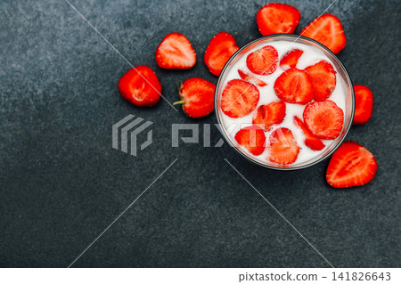 Fresh strawberries topped with cream in a clear glass placed on a dark stone surface Fresh strawberries topped with cream in a clear glass placed on a dark stone surface 141826643