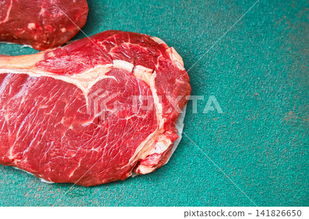 Fresh cut of beef on green surface ready for cooking preparation in kitchen Fresh cut of beef on green surface ready for cooking preparation in kitchen 141826650