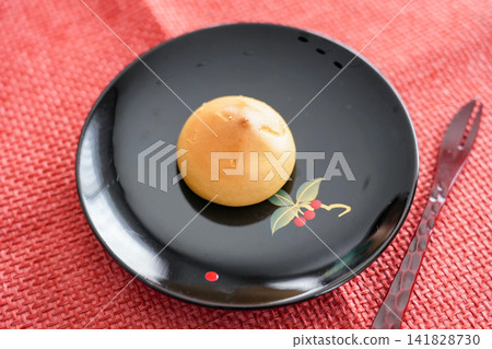 A bun filled with yellow bean paste that stands out against a vermilion mat. A bun filled with yellow bean paste that stands out against a vermilion mat. 141828730