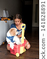 Girl sitting on floor with shih tzu dog in a plastic toy cart 141828891