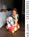 Girl sitting on floor with shih tzu dog in a plastic toy cart 141828892