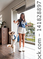 Little fluffy dog jumping up to catch a treat from a young girl 141828897