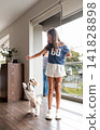 Little fluffy dog jumping up to catch a treat from a young girl 141828898