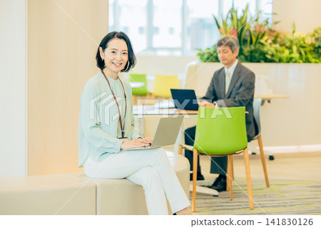 A businesswoman in her 50s working in a co-working space. A businesswoman in her 50s working in a co-working space. 141830126