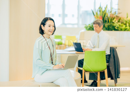 A businesswoman in her 50s working in a co-working space. A businesswoman in her 50s working in a co-working space. 141830127