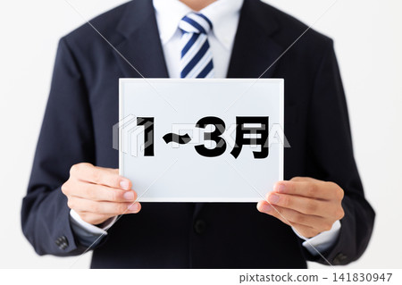 一月至三月,一位身穿西裝的年輕男商務人士手持白板。 一月至三月,一位身穿西裝的年輕男商務人士手持白板。 141830947