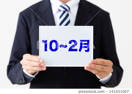 A young male businessman in a business suit holding a whiteboard, taken between October and February. A young male businessman in a business suit holding a whiteboard, taken between October and February. 141831007
