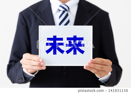 A young businessman in a business suit holding a whiteboard of the future. A young businessman in a business suit holding a whiteboard of the future. 141831138