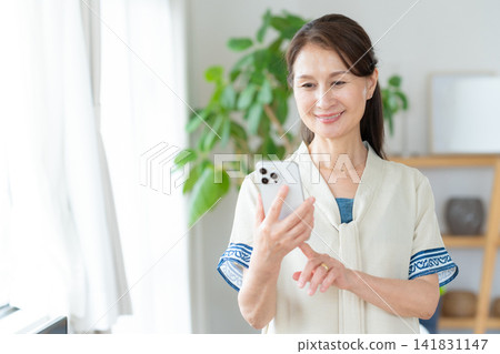 Senior woman looking at smartphone in living room Senior woman looking at smartphone in living room 141831147