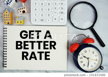 Get A Better Rate text written on notepad with house model, calculator, magnifying glass and alarm clock on marble background 141831480