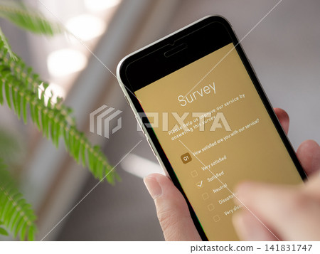 一張特寫照片,展示了一位女士正在用智慧型手機填寫問卷的雙手(螢幕為原創設計)。英文版。 一張特寫照片,展示了一位女士正在用智慧型手機填寫問卷的雙手(螢幕為原創設計)。英文版。 141831747