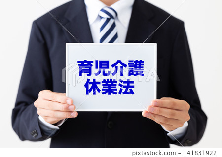 A young businessman in a business suit holding a whiteboard about the Childcare and Family Care Leave Act. A young businessman in a business suit holding a whiteboard about the Childcare and Family Care Leave Act. 141831922