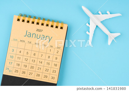 January 2027 calendar and airplane toy on blue background. January 2027 calendar and airplane toy on blue background. 141831980