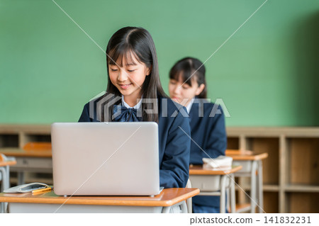 Female middle and high school students in uniform studying using computers. Female middle and high school students in uniform studying using computers. 141832231