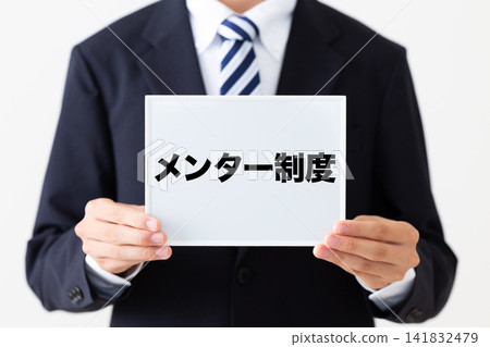 A young businessman in a business suit holding a whiteboard for a mentoring program. A young businessman in a business suit holding a whiteboard for a mentoring program. 141832479
