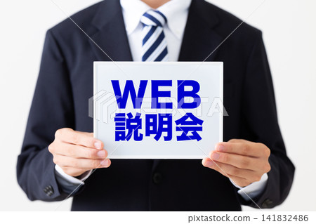 A young businessman in a business suit holding a whiteboard during a web-based information session. A young businessman in a business suit holding a whiteboard during a web-based information session. 141832486