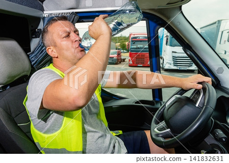 Thirsty van driver drinking water from a plastic bottle in a cabin Thirsty van driver drinking water from a plastic bottle in a cabin 141832631