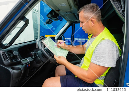 Logistics worker signing a delivery contract on a clipboard inside a van Logistics worker signing a delivery contract on a clipboard inside a van 141832633