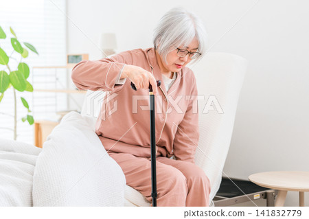 一位穿著睡衣的老婦人起床時抱怨膝蓋疼痛(膝蓋,膝蓋疼痛) 一位穿著睡衣的老婦人起床時抱怨膝蓋疼痛(膝蓋,膝蓋疼痛) 141832779