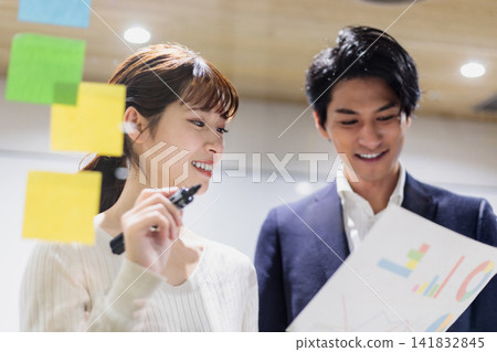 A businessman having a meeting using a transparent board in a conference room A businessman having a meeting using a transparent board in a conference room 141832845