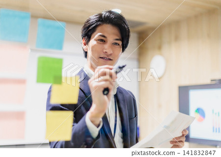 一名男子在會議室裡做報告,手裡拿著文件。 一名男子在會議室裡做報告,手裡拿著文件。 141832847