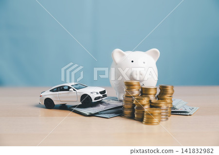 Piggy bank with white toy car, coin stacks, and cash, representing saving money for car purchase, down payment, auto loan planning, vehicle finance, and ownership budget. Piggy bank with white toy car, coin stacks, and cash, representing saving money for car purchase, down payment, auto loan planning, vehicle finance, and ownership budget. 141832982