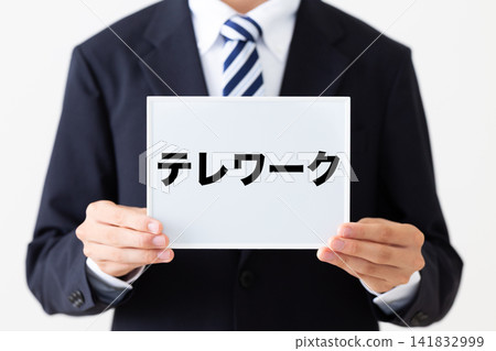 A young businessman in a business suit holding a whiteboard for teleworking. A young businessman in a business suit holding a whiteboard for teleworking. 141832999