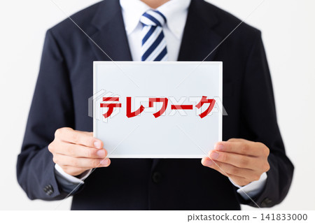 A young businessman in a business suit holding a whiteboard for teleworking. A young businessman in a business suit holding a whiteboard for teleworking. 141833000