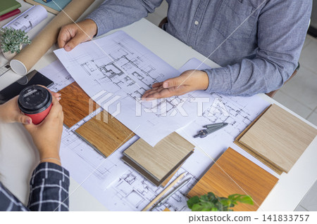 Interior designer reviewing apartment layout blueprint and materials at desk. Interior designer reviewing apartment layout blueprint and materials at desk. 141833757