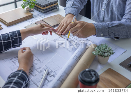 Architects and interior teamwork cooperate on plan project design and choosing material for home interior, drawing on blueprint. Architects and interior teamwork cooperate on plan project design and choosing material for home interior, drawing on blueprint. 141833784