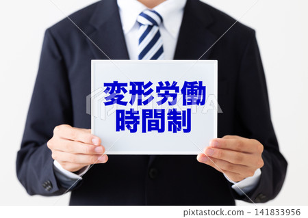 一位身穿西裝的年輕商人,手持一塊白板,上面寫著彈性工時制度。 一位身穿西裝的年輕商人,手持一塊白板,上面寫著彈性工時制度。 141833956