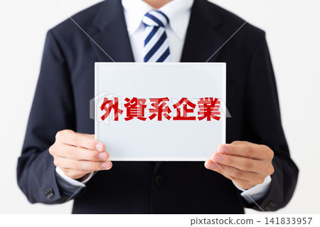 一位身穿西裝的年輕商務人士在一家外國公司裡拿著白板。 141833957