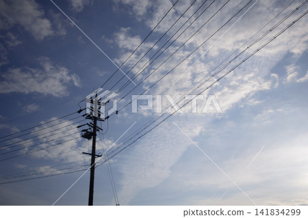 (Different composition) The silhouette of a telephone pole against the autumn morning glow, with contrails dissolving into cirrocumulus clouds in the sky. 141834299