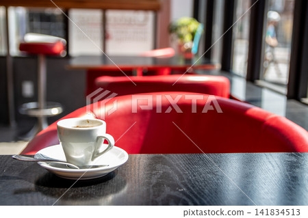 An espresso placed on a cafe table in a red booth seat. An espresso placed on a cafe table in a red booth seat. 141834513