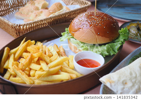 Delicious burger with fries served at a restaurant Delicious burger with fries served at a restaurant 141835342