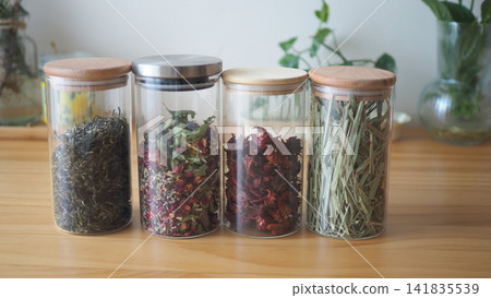 Glass jars with herbs and flowers on a wooden table 141835539