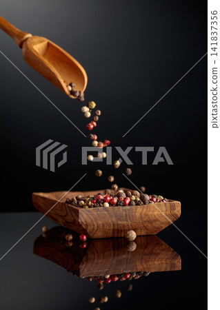 Black, red, white, and allspice peppercorns is poured in wooden dish. Black, red, white, and allspice peppercorns is poured in wooden dish. 141837356