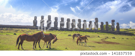 Wild horses grazing near ancient moai statues of Ahu Tongariki in Easter Island, panorama with copy space Wild horses grazing near ancient moai statues of Ahu Tongariki in Easter Island, panorama with copy space 141837559