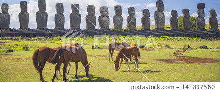 Horses on pasture in front of stone moai statues of Ahu Tongariki in Easter Island, panorama with copy space Horses on pasture in front of stone moai statues of Ahu Tongariki in Easter Island, panorama with copy space 141837560